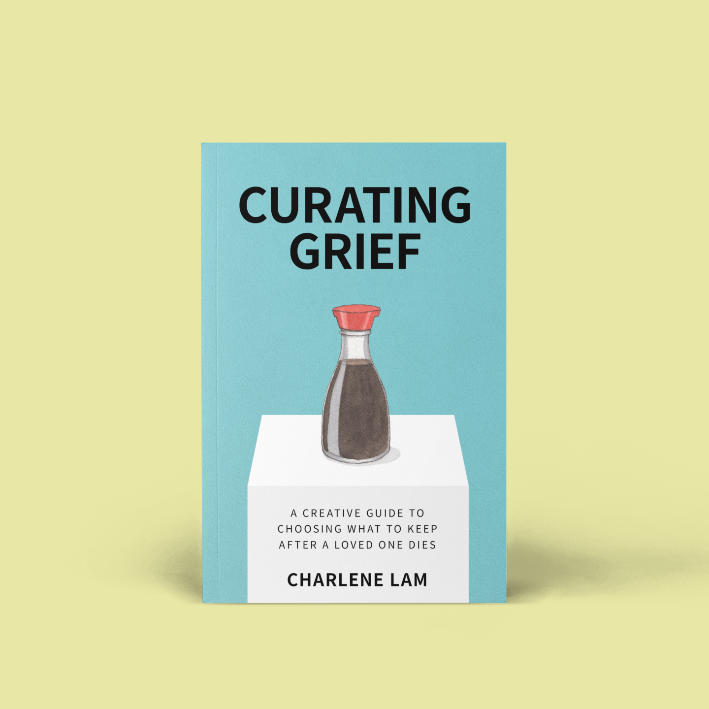 The Grief Gallery in Toronto for DesignTO, Jan 2022. Gallery space with Asian woman with white display pedestals and wooden bookcase with items displayed like vintage travel bag