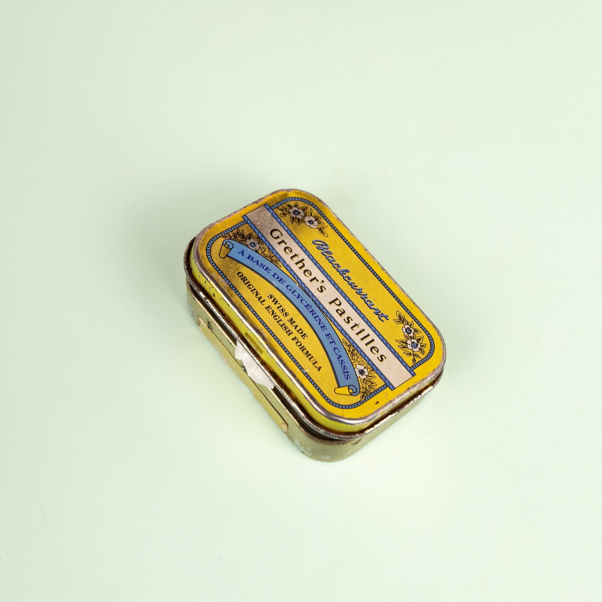 the-grief-gallery-marilyns-vitamins-tin-square-1920x1920px Hands with file label with "Grief" misspelled as "Greif"